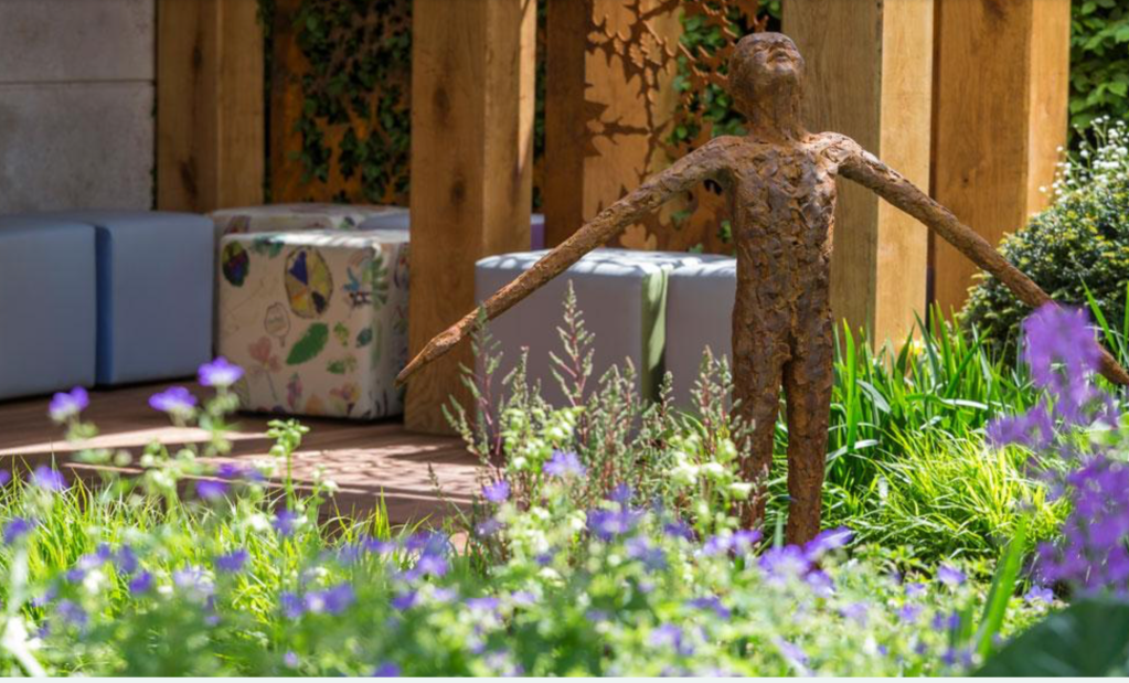 Stature of child smiling surrounded by plants and flowers 
