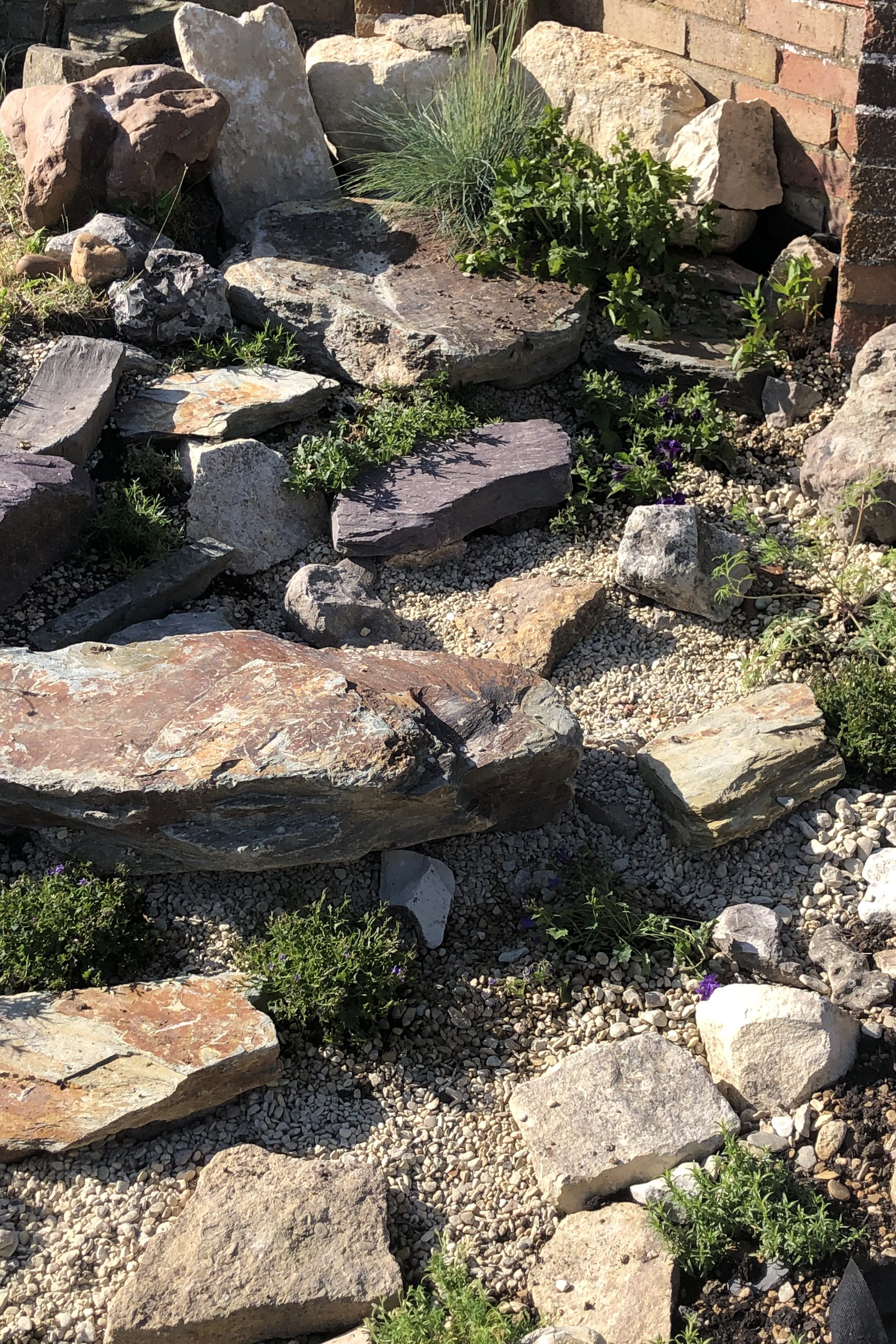 Large slate and warm cream stone surrounded by young plants