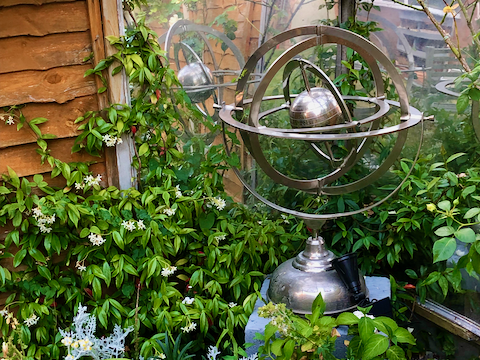 Chrome armillary surrounded by pale flowering plants
